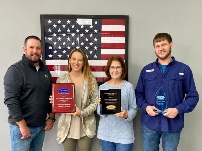 Four members of the Buffington Brothers leadership team holding Carrier President's Award and Carrier Factory Authorized Dealer plaques in front of an American flag.